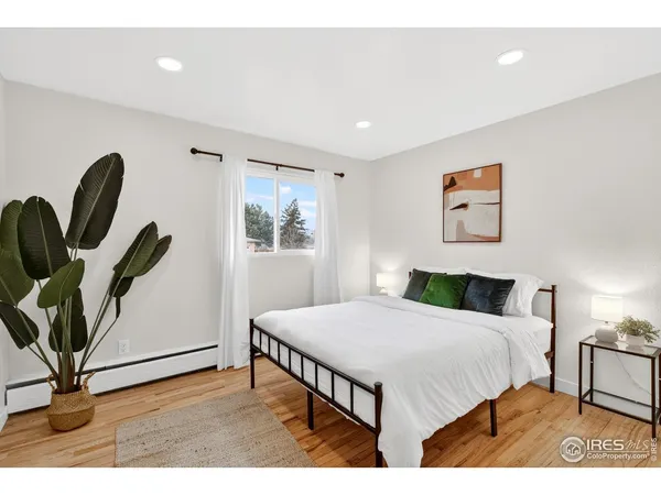a bedroom with a bed a couch and a potted plant on the dresser