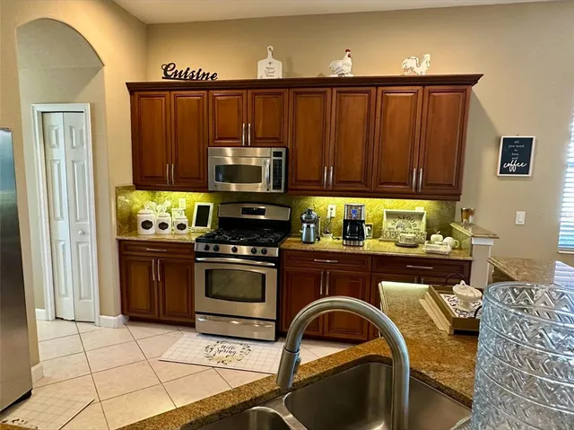 a kitchen with stainless steel appliances granite countertop a stove a sink and a microwave