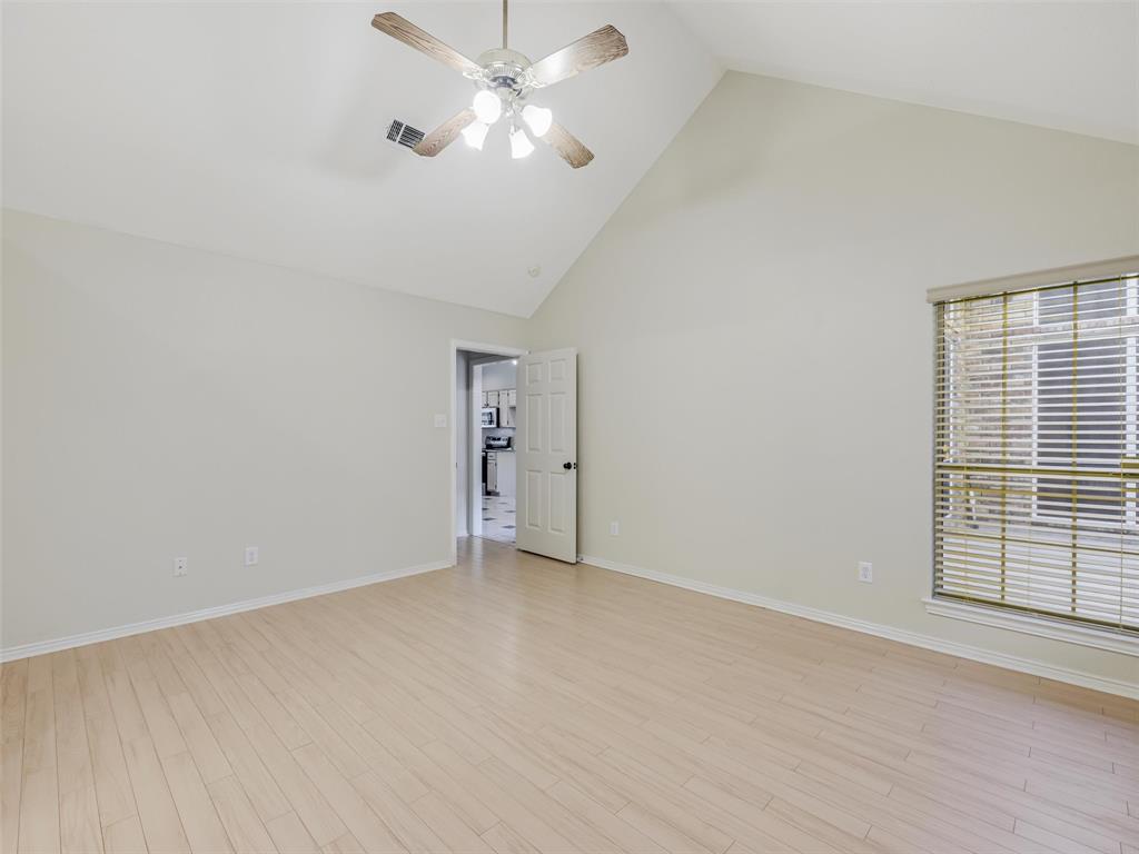 7836 Tournament Road Frisco, TX 75035 - Photo 14 of 23 Vaulted ceiling with an attached ceiling fan, wood-finish flooring, a white paneled door, and a window with blinds