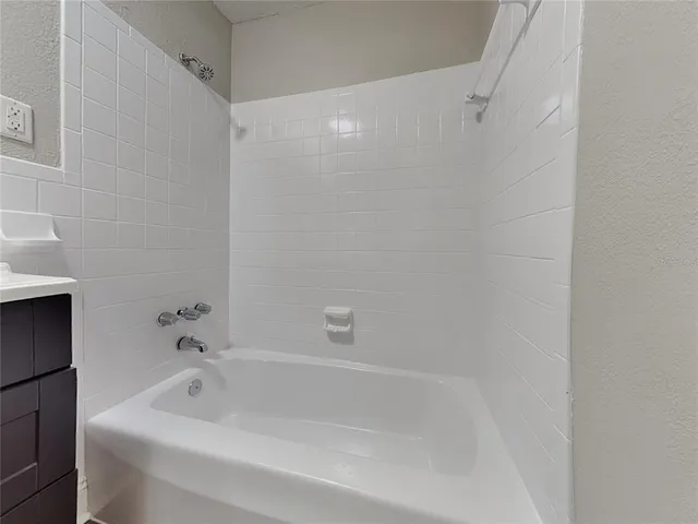 a white bath tub sitting next to a white sink and vanity