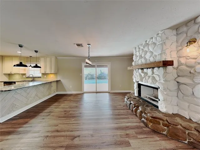 a living room with stainless steel appliances wooden floor and a fireplace