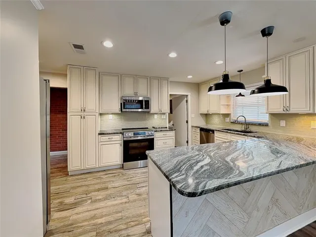 a kitchen with stainless steel appliances granite countertop a sink refrigerator and cabinets