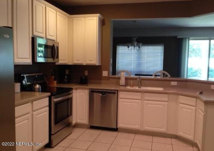 a kitchen with white cabinets a sink and appliances