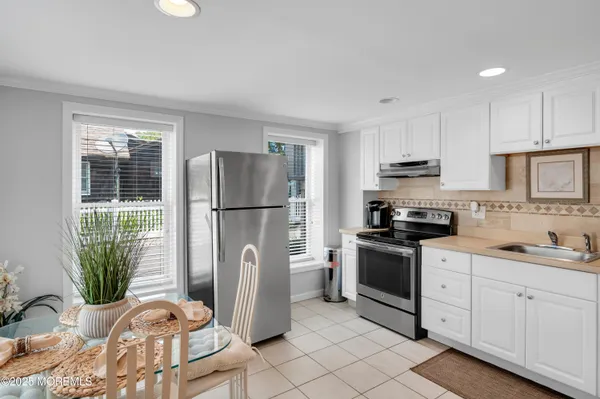 a kitchen with stainless steel appliances a refrigerator a stove a sink a microwave a dining table and chairs