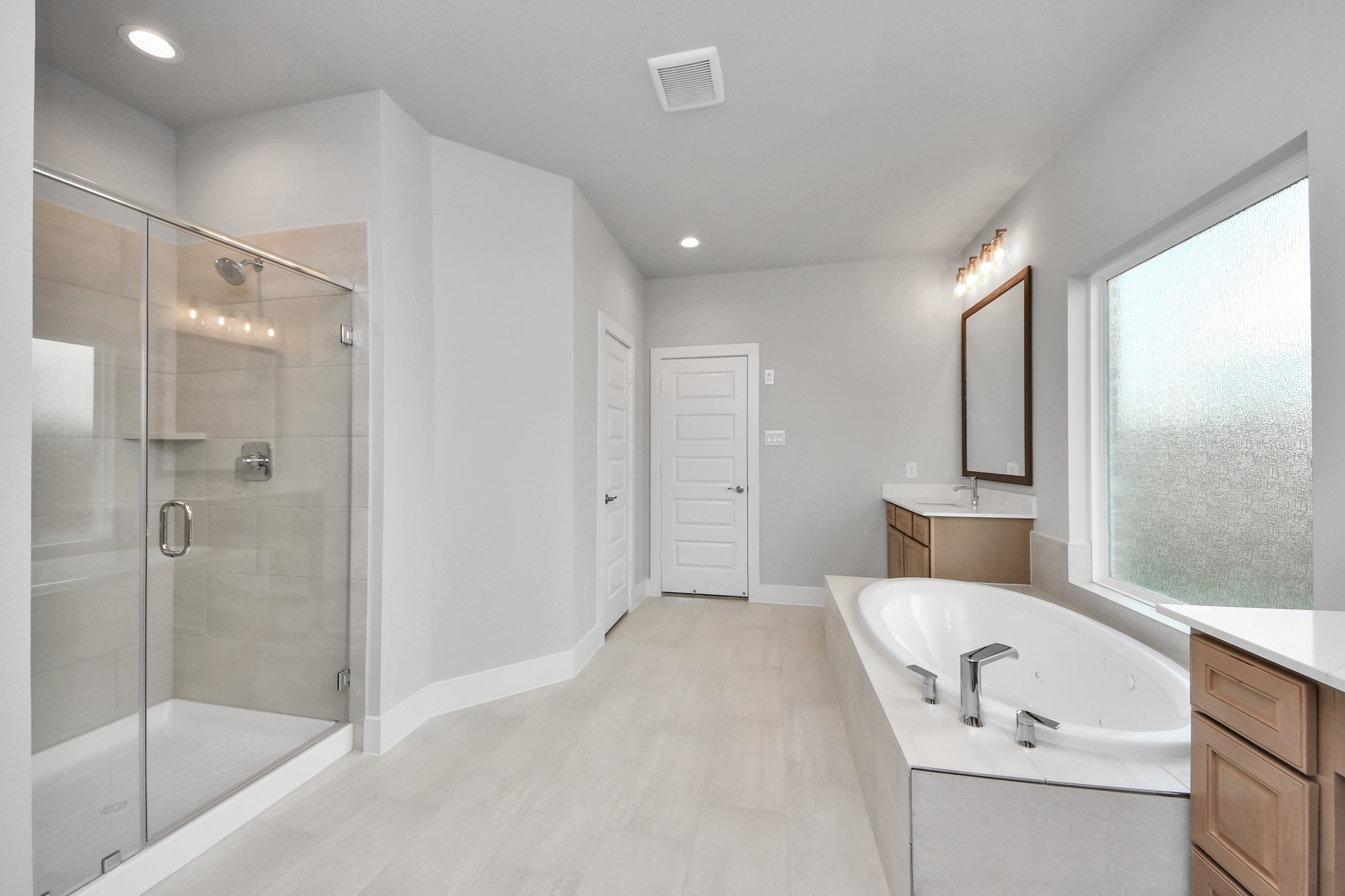 3109 North Spring Drive Spring, TX 77373 - Photo 28 of 50 Escape to a spa-like oasis in this primary bathroom. Enjoy a walk-in shower with tile surround, a separate garden tub with custom detailing, and an elegant vanity featuring light countertops, modern hardware, and beautiful vanity lights. Experience luxury and relaxation in every detail.