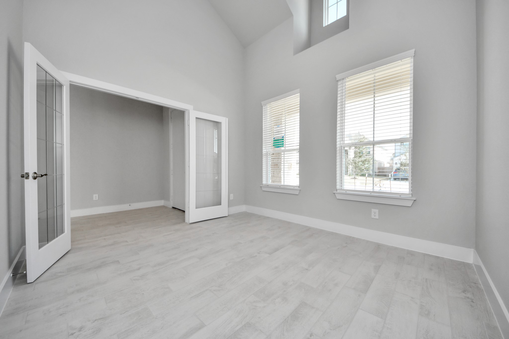 3109 North Spring Drive Spring, TX 77373 - Photo 7 of 50 Experience the perfect blend of sophistication and warmth in this home office, boasting elegant wood-look tile flooring and flooded with natural light from expansive windows and French doors.