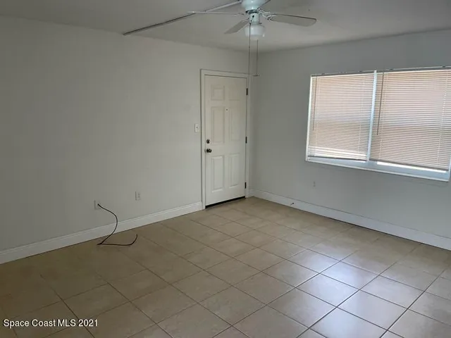 an empty room with a ceiling fan and window