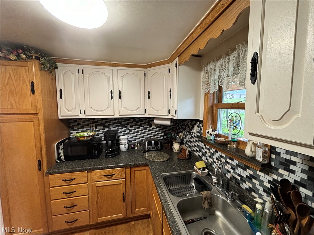 2417 Mc Adoo Ridge Road Wellsburg, WV 26070 - Photo 3 of 33 Kitchen with sink, wood-type flooring, tasteful backsplash, and white cabinetry