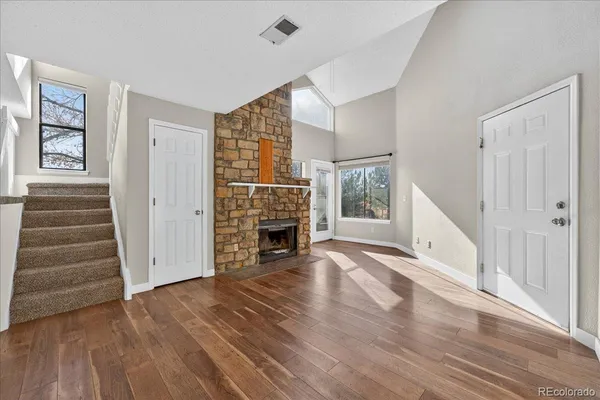 an empty room with wooden floor fireplace and windows