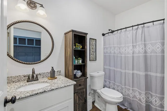 a bathroom with a granite countertop sink mirror vanity and toilet