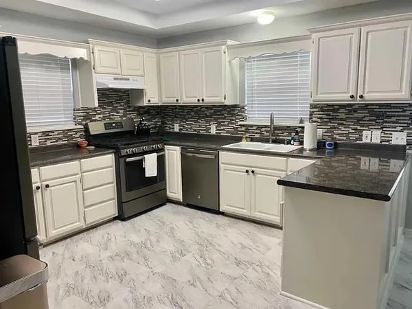 a kitchen with stainless steel appliances granite countertop a stove sink and cabinets