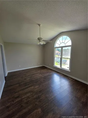 an empty room with wooden floor chandelier and windows