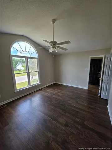 an empty room with wooden floor fan and windows