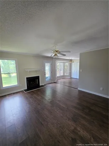 an empty room with wooden floor fireplace and windows