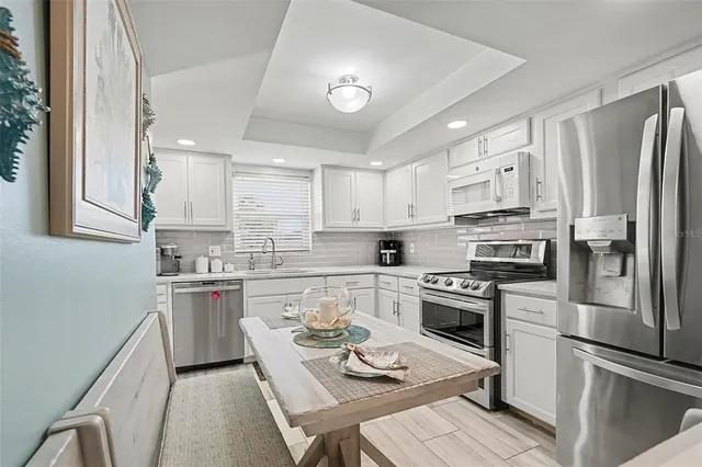 a kitchen with stainless steel appliances a stove a sink dishwasher a refrigerator white cabinets and wooden floor
