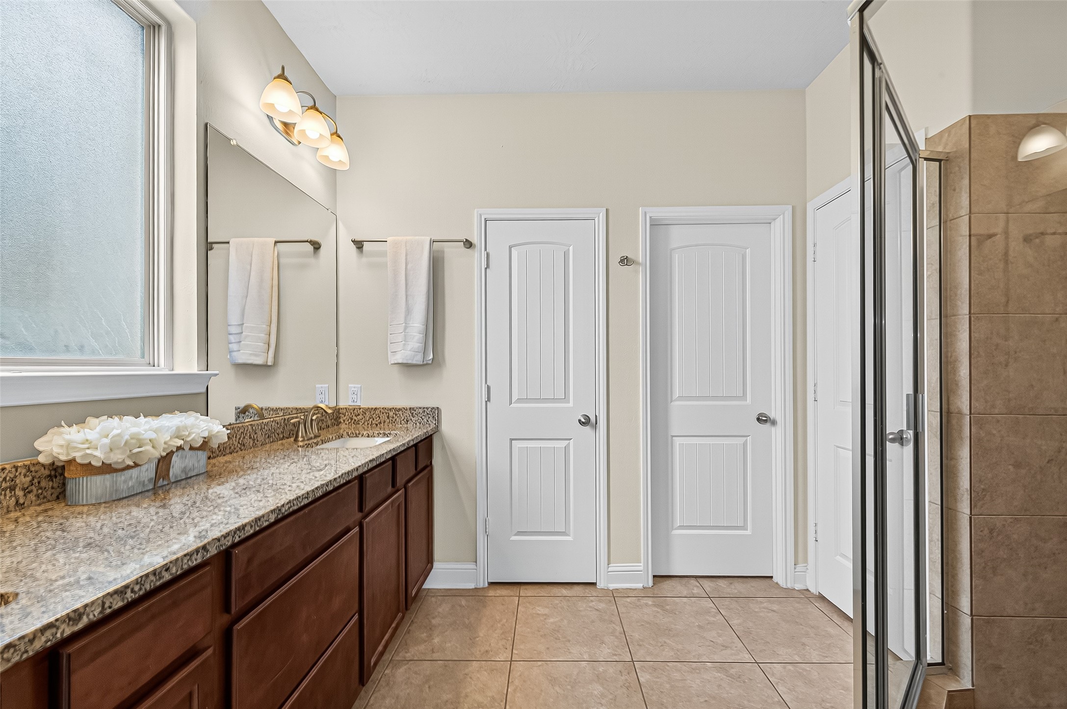 8107 Lockridge Terrace Lane Cypress, TX 77433 - Photo 31 of 50 The primary bathroom offers a spa-like escape with dual sinks set in granite countertops, a large glass-enclosed shower, and beautiful tile flooring. Crisp, neutral finishes and abundant natural light create a fresh and calming space—ideal for both energizing mornings and relaxing evenings.