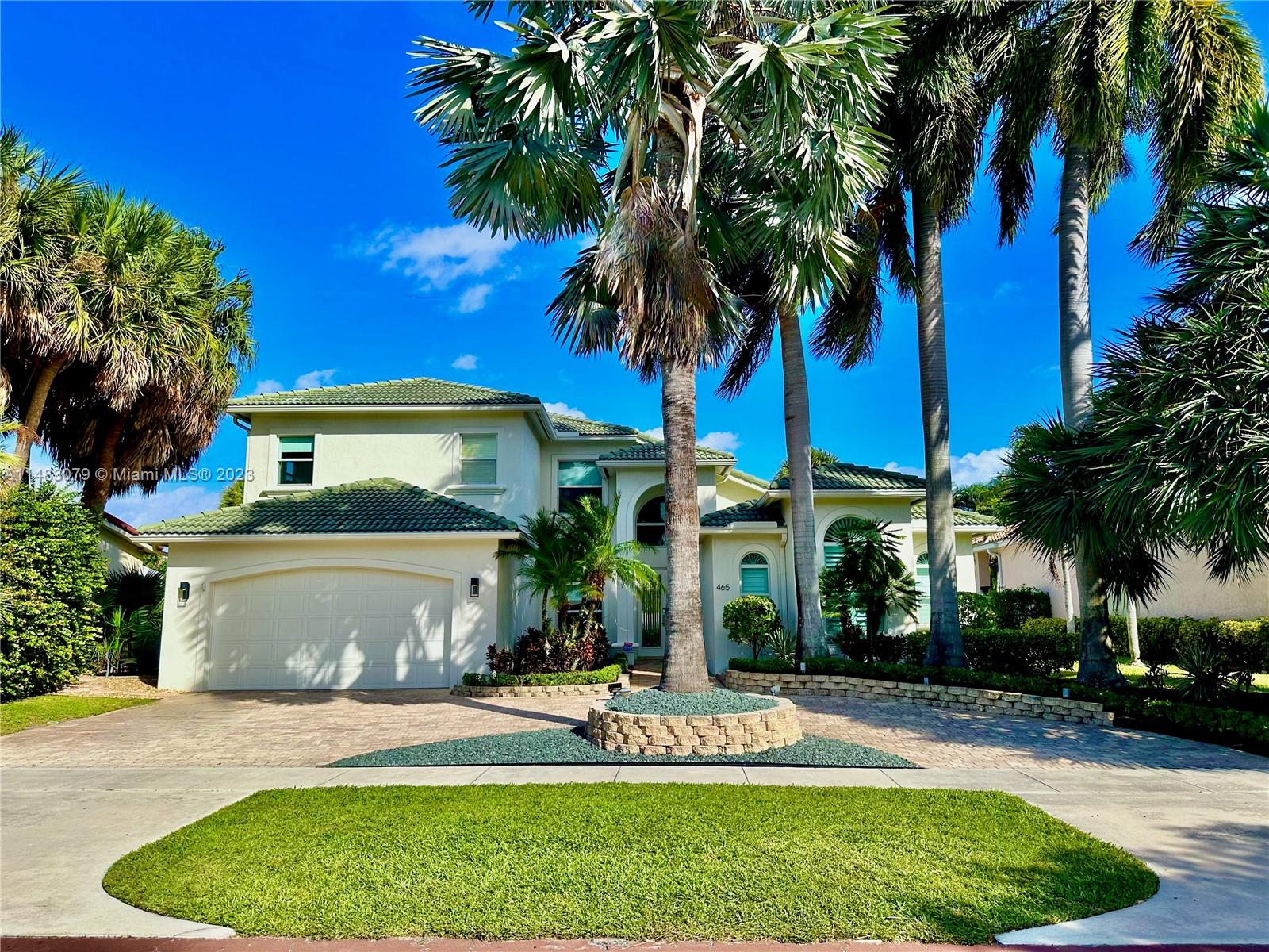 a front view of a house with a garden and tree