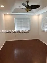 a view of an empty room with wooden floor and a ceiling fan