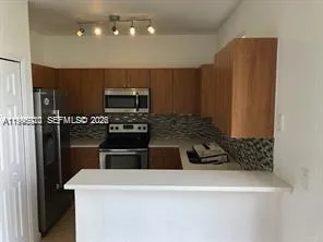 a kitchen with granite countertop a refrigerator a stove a microwave and island