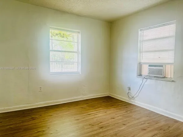 a view of an empty room with a window and wooden floor