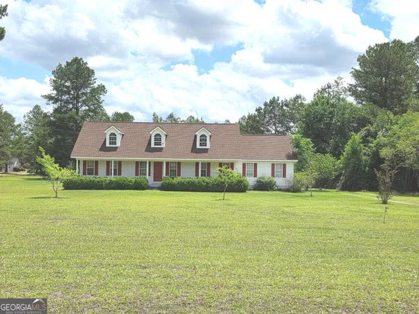 a view of a big house with a big yard and large trees