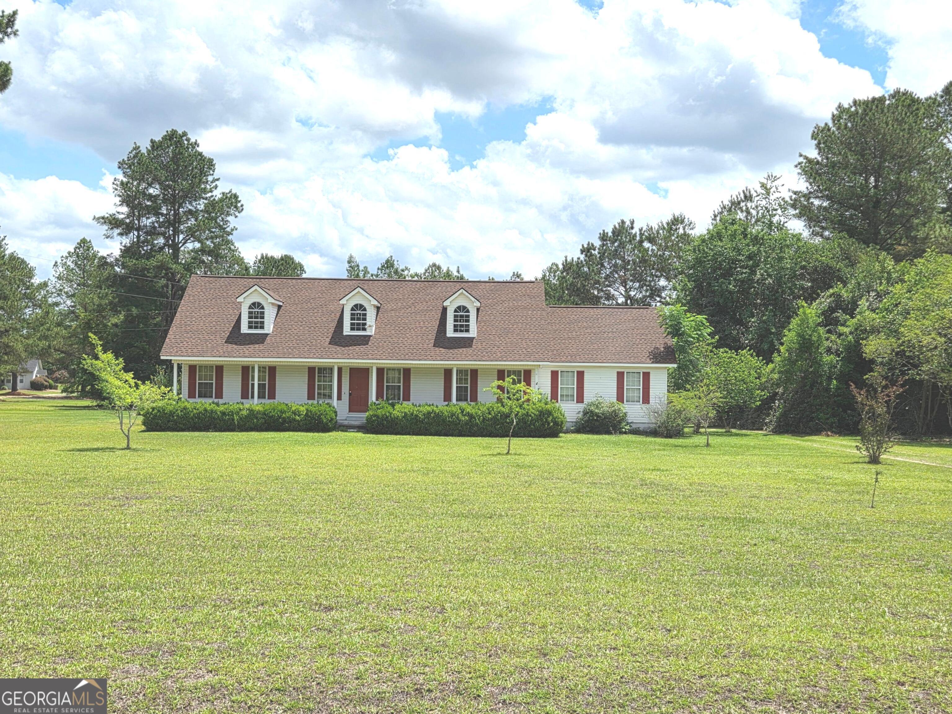a view of a big house with a big yard and large trees