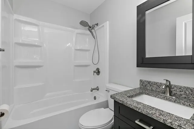 a bathroom with a granite countertop sink toilet and shower
