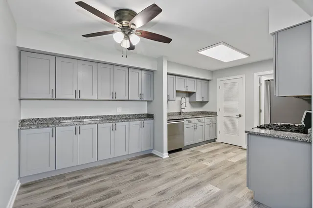 a kitchen with stainless steel appliances a stove a sink and white cabinets