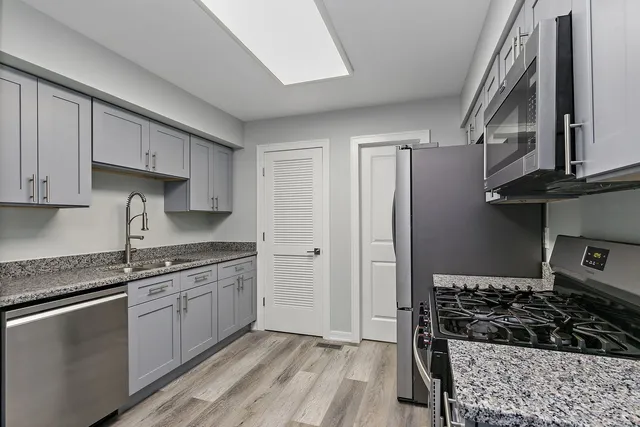 a kitchen with stainless steel appliances granite countertop a stove a sink and a refrigerator