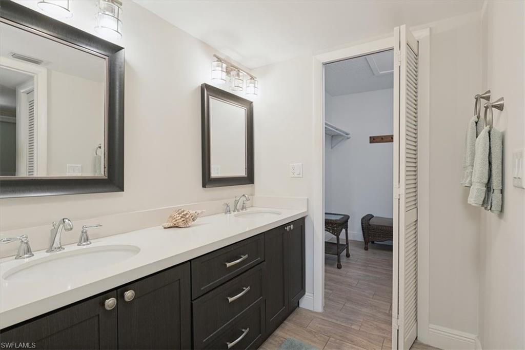 75 St Andrews Boulevard, Unit C301 Naples, FL 34113 - Photo 17 of 42 a en suite bathroom with a double vanity sink a mirror a window and a shower