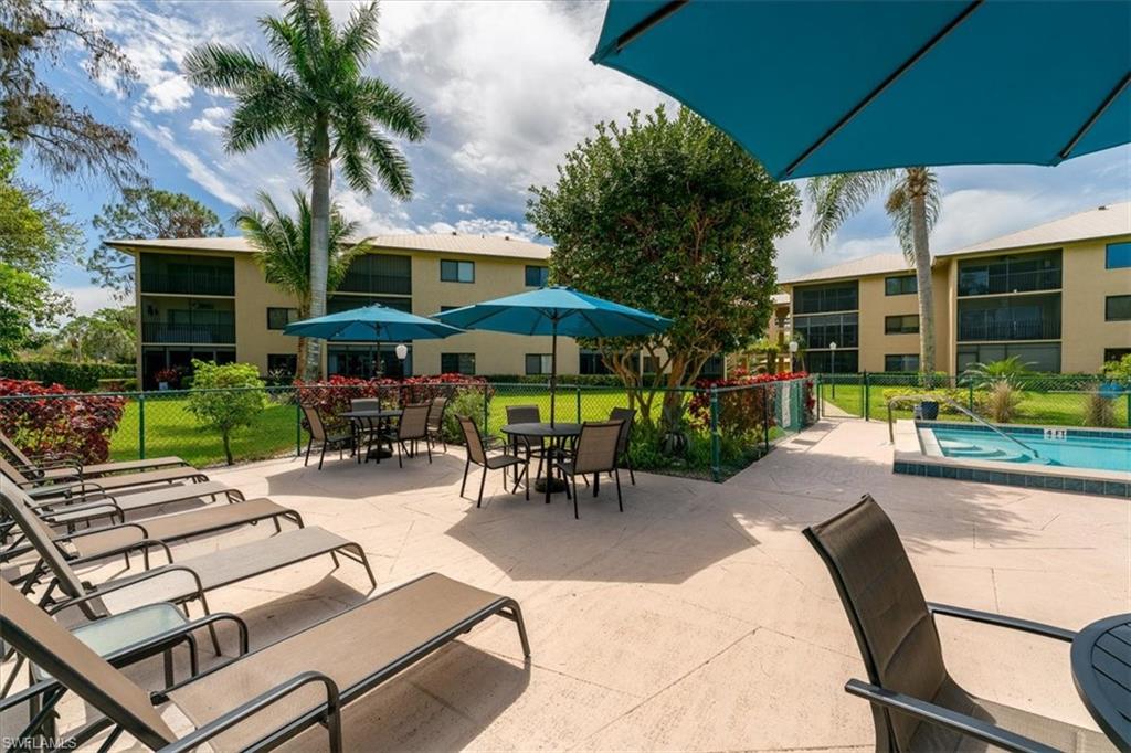 75 St Andrews Boulevard, Unit C301 Naples, FL 34113 - Photo 31 of 42 a view of a patio with a table and chairs under an umbrella