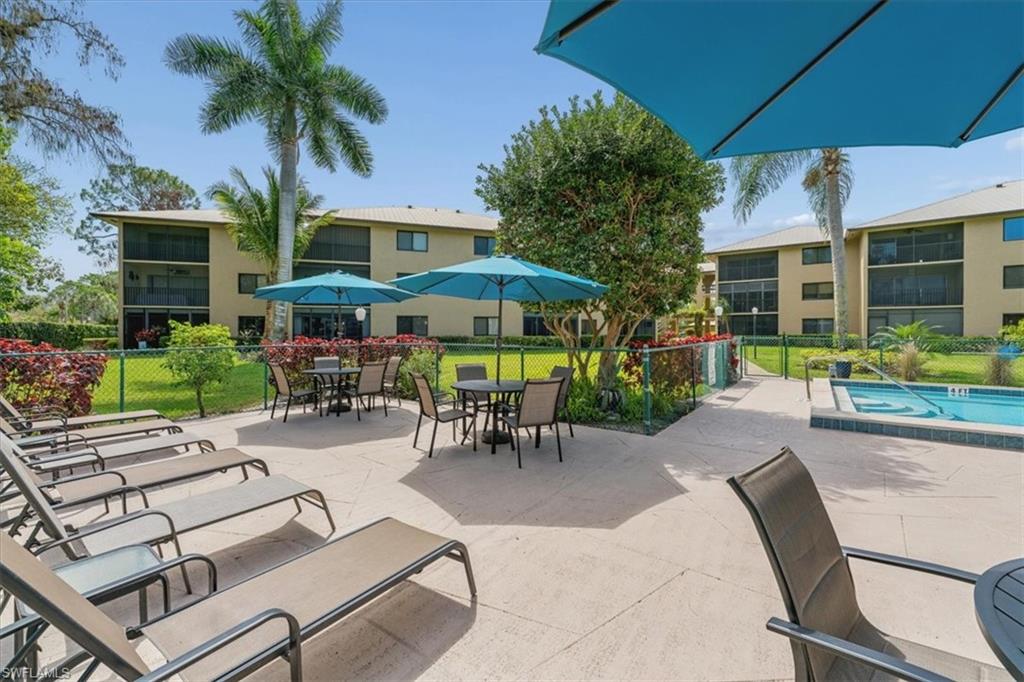 75 St Andrews Boulevard, Unit C301 Naples, FL 34113 - Photo 35 of 42 a view of a patio with a table and chairs under an umbrella