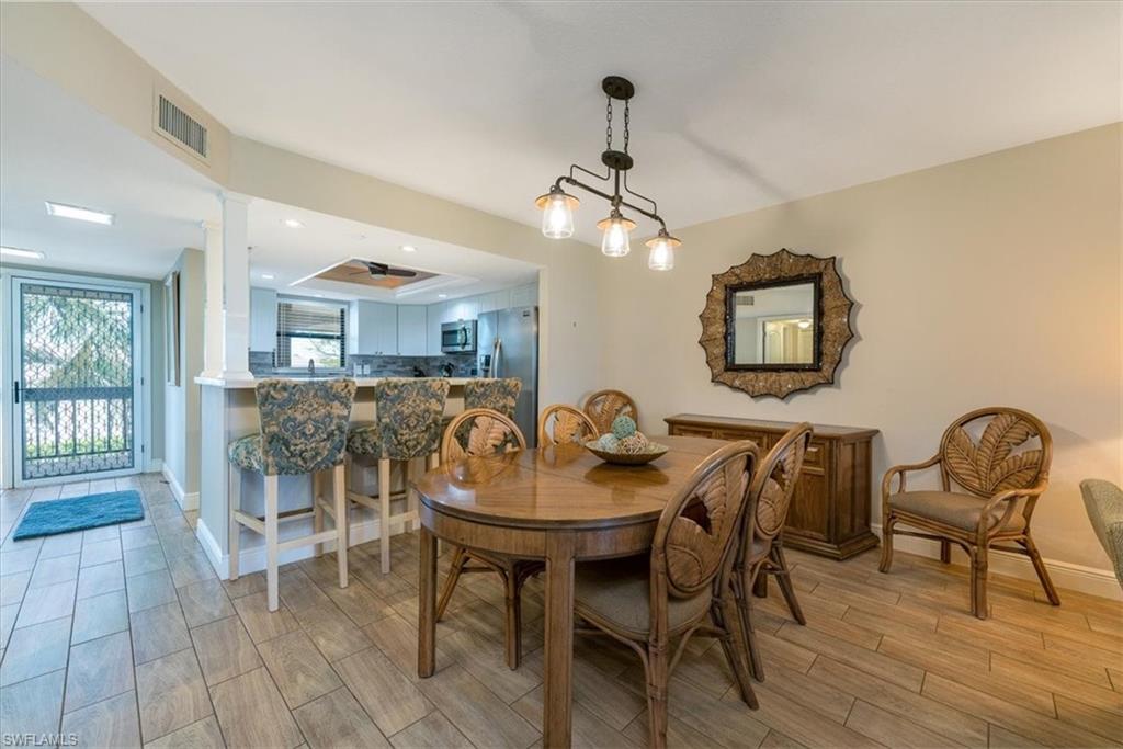 75 St Andrews Boulevard, Unit C301 Naples, FL 34113 - Photo 10 of 42 a view of a dining room with furniture and wooden floor