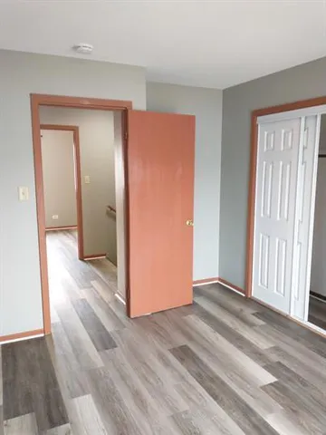 an empty room with wooden floor and a bathroom