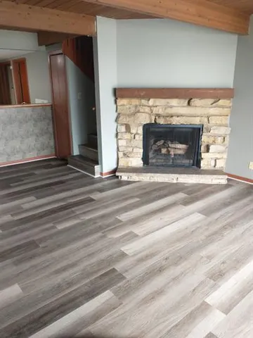 a view of an empty room with wooden floor and a fireplace