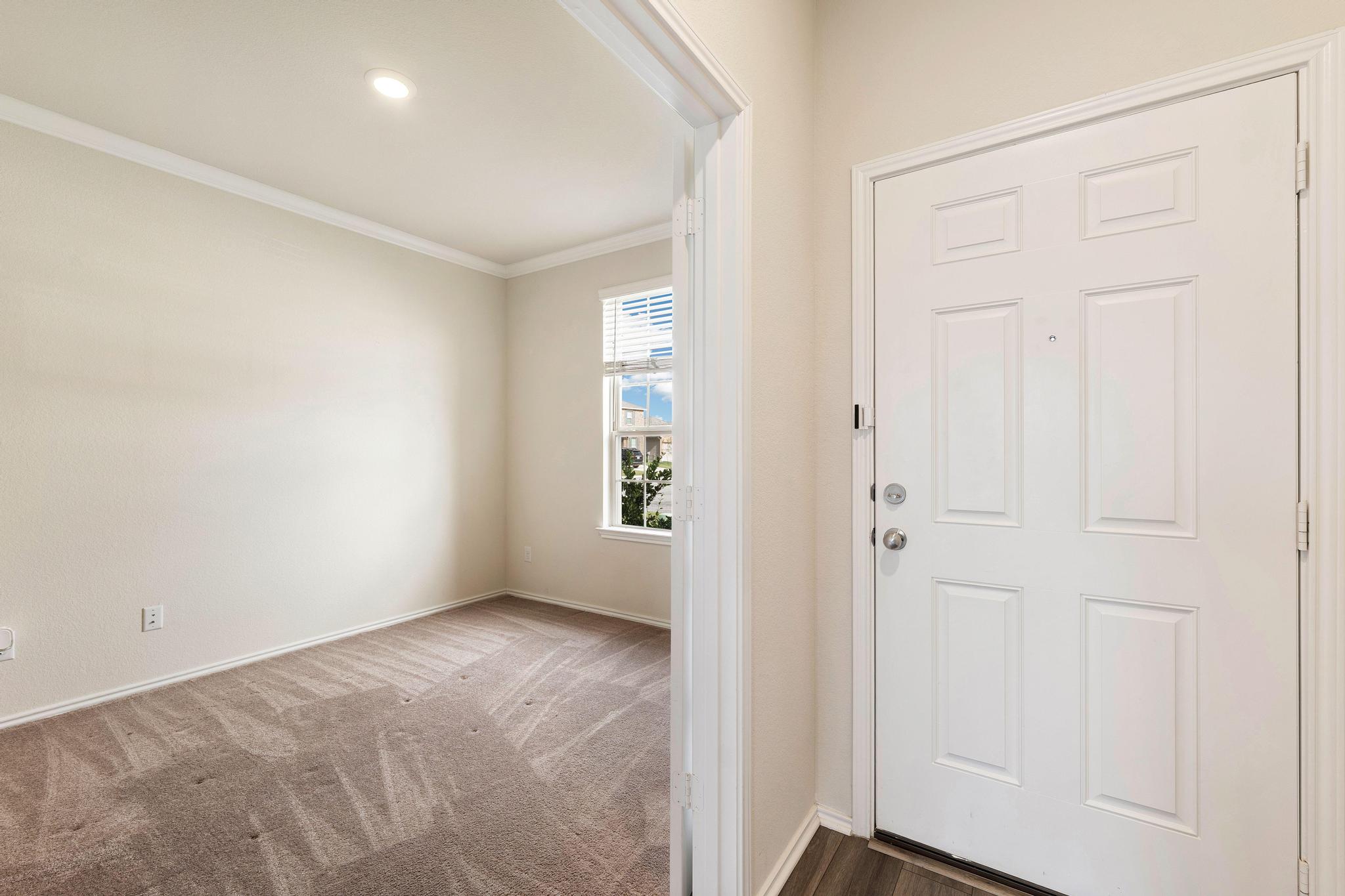 217 Innisfree Road Jarrell, TX 76537 - Photo 4 of 39 A welcoming entry, boasting a bright white door and wood-look flooring, opens to a carpeted interior space.