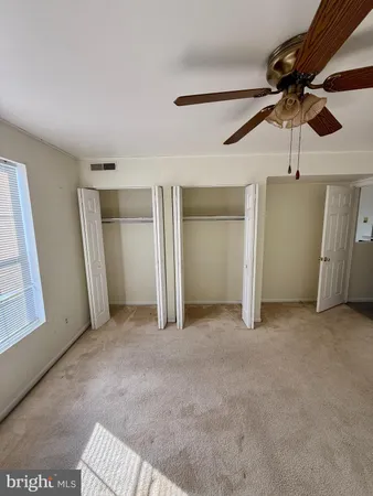 an empty room with a ceiling fan and windows