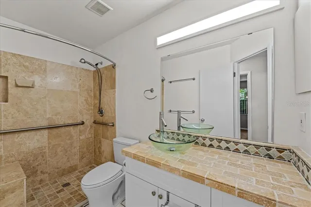 a bathroom with a granite countertop sink mirror vanity and toilet