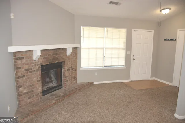a view of an empty room with a fireplace and a window