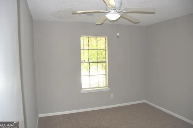 an empty room with windows and fan