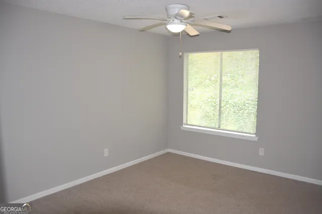 an empty room with a window and a fan