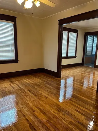 a view of an empty room with wooden floor and windows