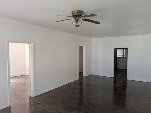 a view of a room with wooden floor ceiling fan and window