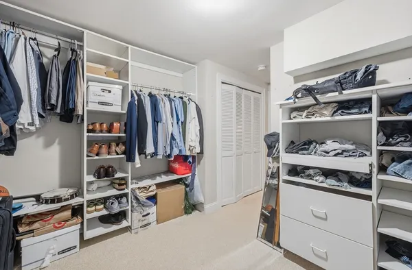 a view of walk in closet with clothes and shoes