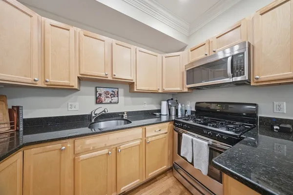 a kitchen with granite countertop a sink a stove and cabinets