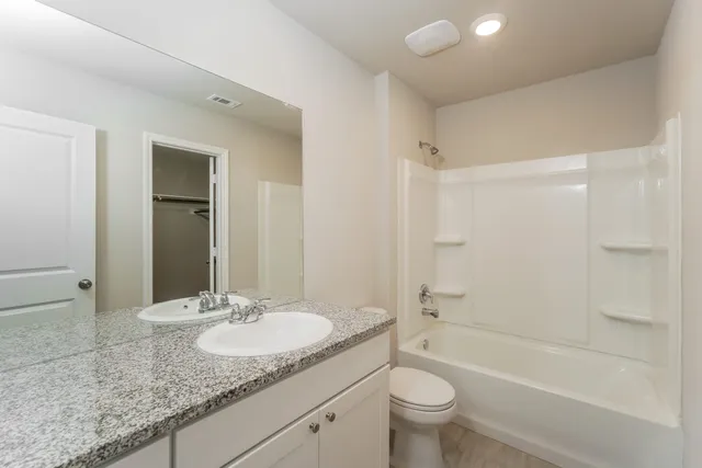 a bathroom with a granite countertop sink a toilet and shower