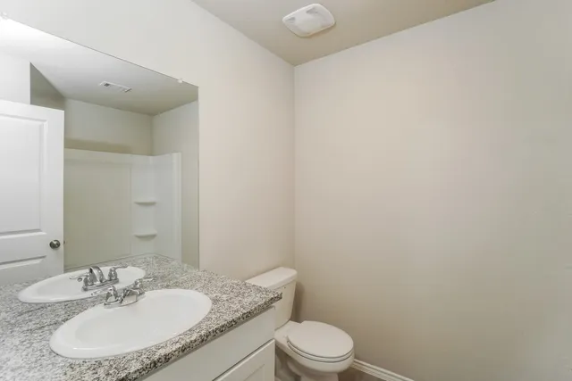 a bathroom with a granite countertop sink a toilet and a mirror