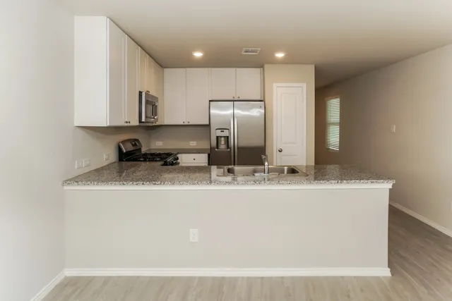 a view of a kitchen with stainless steel appliances granite countertop a sink and a refrigerator