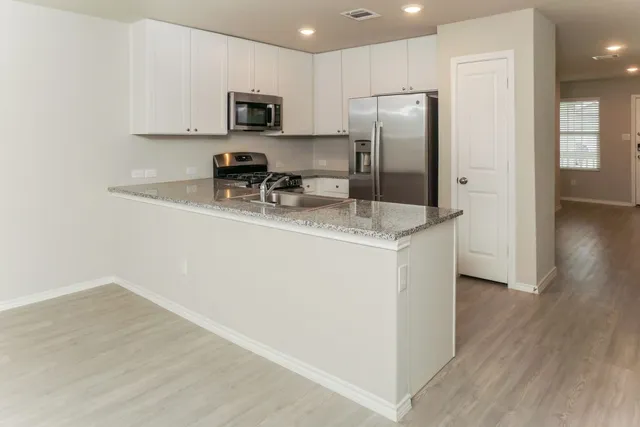 a kitchen with stainless steel appliances granite countertop a refrigerator sink and microwave