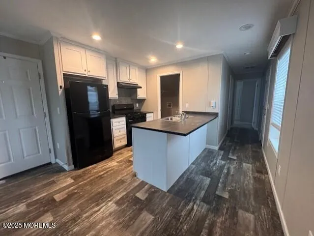 a kitchen with kitchen island granite countertop wooden floors appliances and cabinets